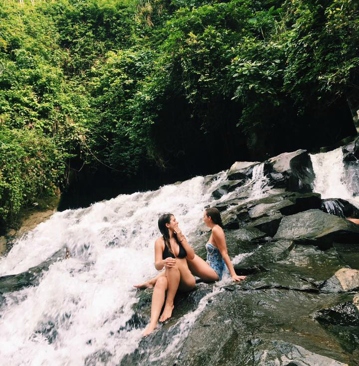 Two girls sitting in a waterfall in Ubud, Bali